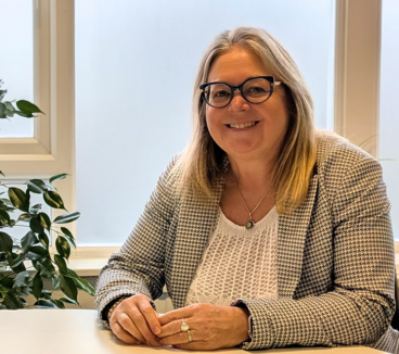 Photo of Jan Marriott smiling at the camera, sat at her desk